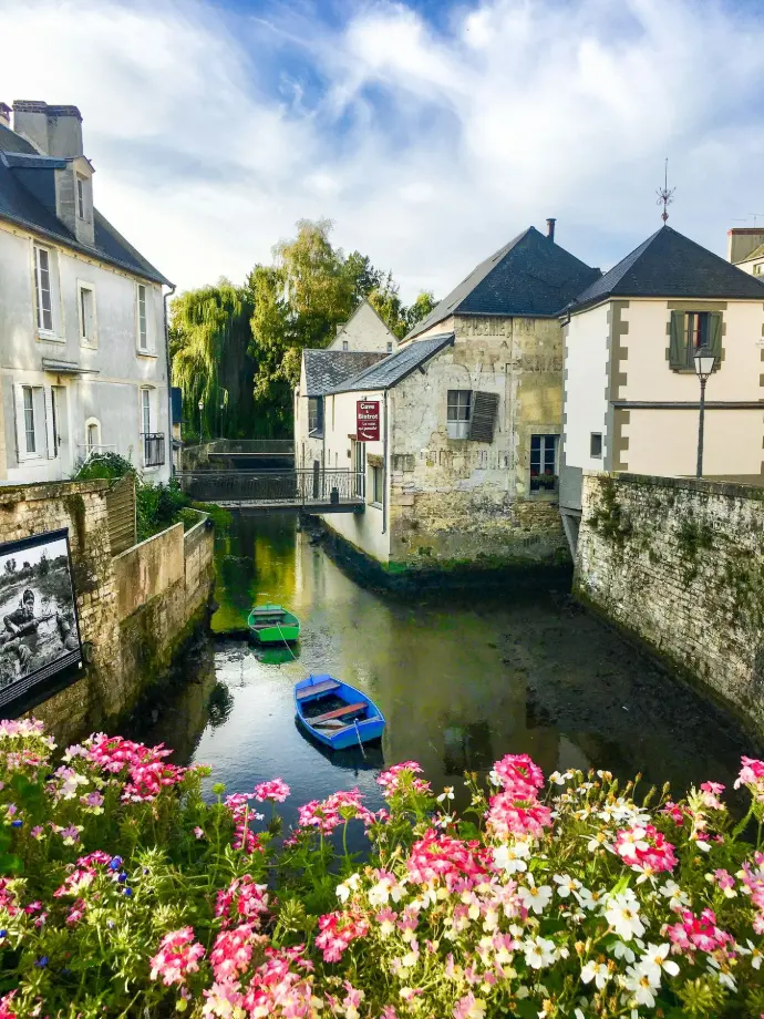 A river running through a small town surrounded by flowers